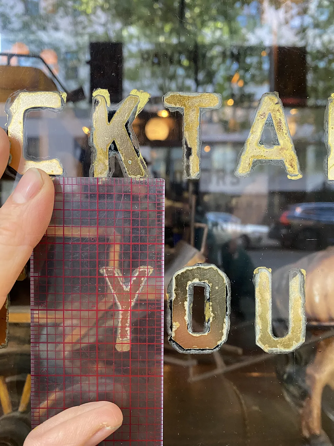 very old gold letters with a ruler held up to them 
